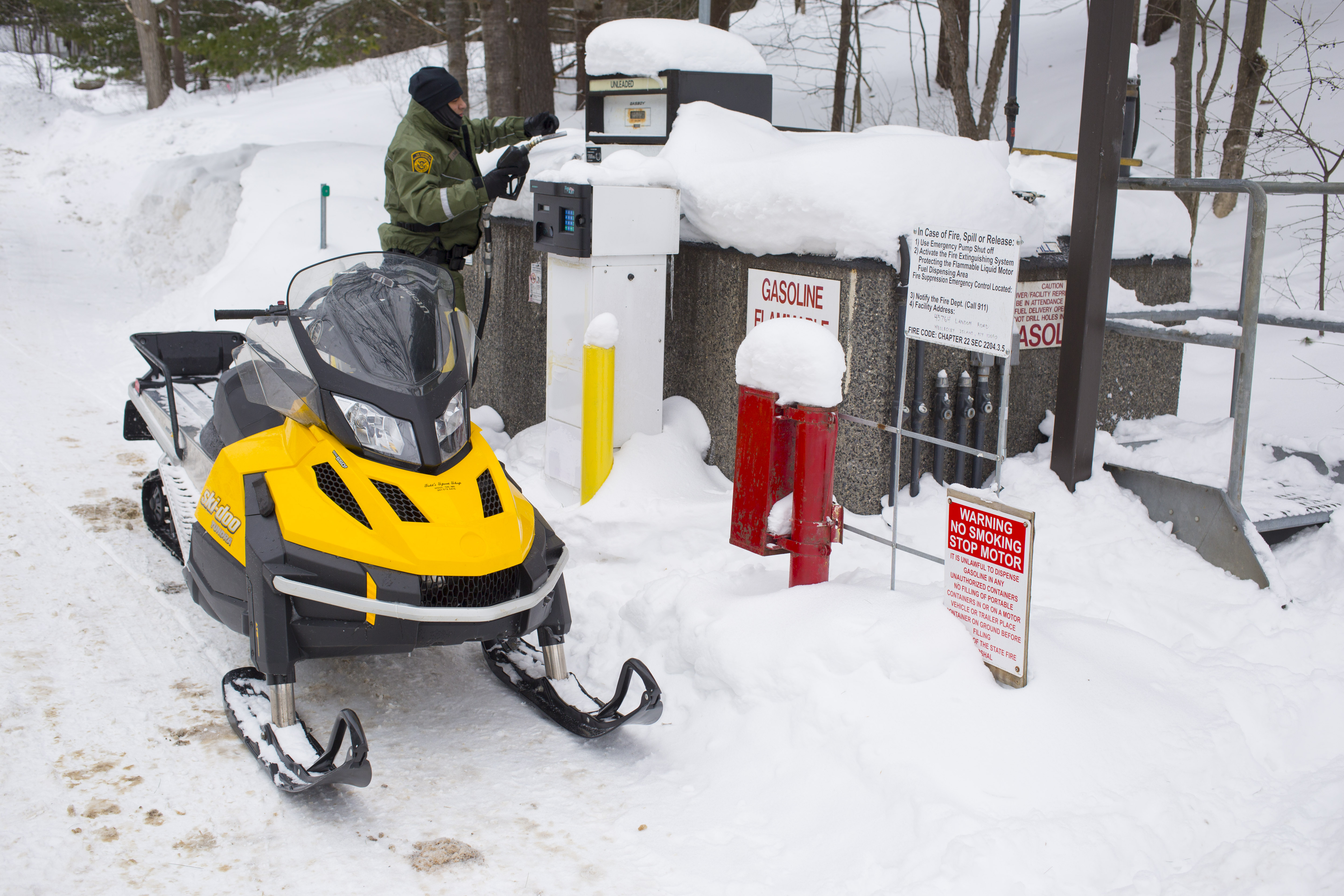 Photo of Border Patrol agent filling his snowmobile with gasoline.