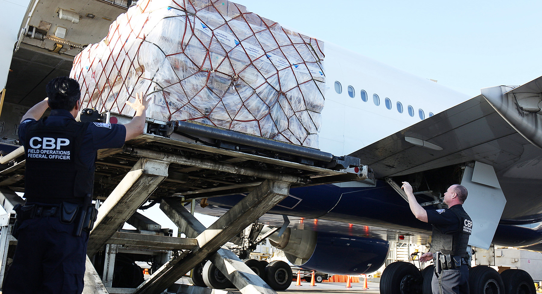 CBP officers are offloading de minimis shipments from a plane at Los Angeles International Airport.