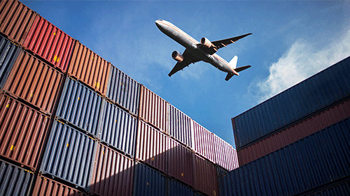 Airplane flying over cargo containers.