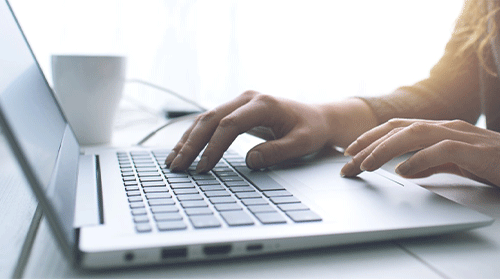 Hands typing on laptop keyboard.