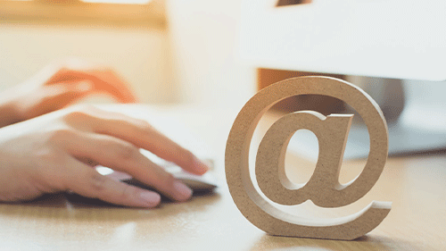 Hands with mouse next to wooden email symbol