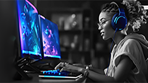 A Woman wearing headphone sitting in front of two computer screens