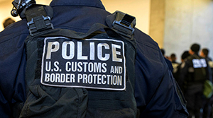 File image of a CBP officer observing international travelers in a CBP inspection facility. 