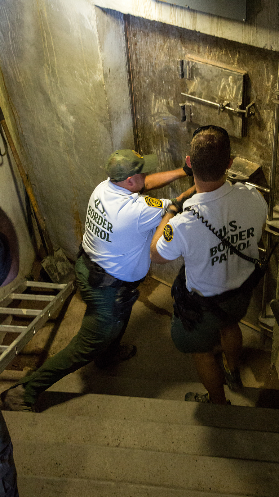 Photo of Border Patrol agents opening an entrance to an area in the drainage system.