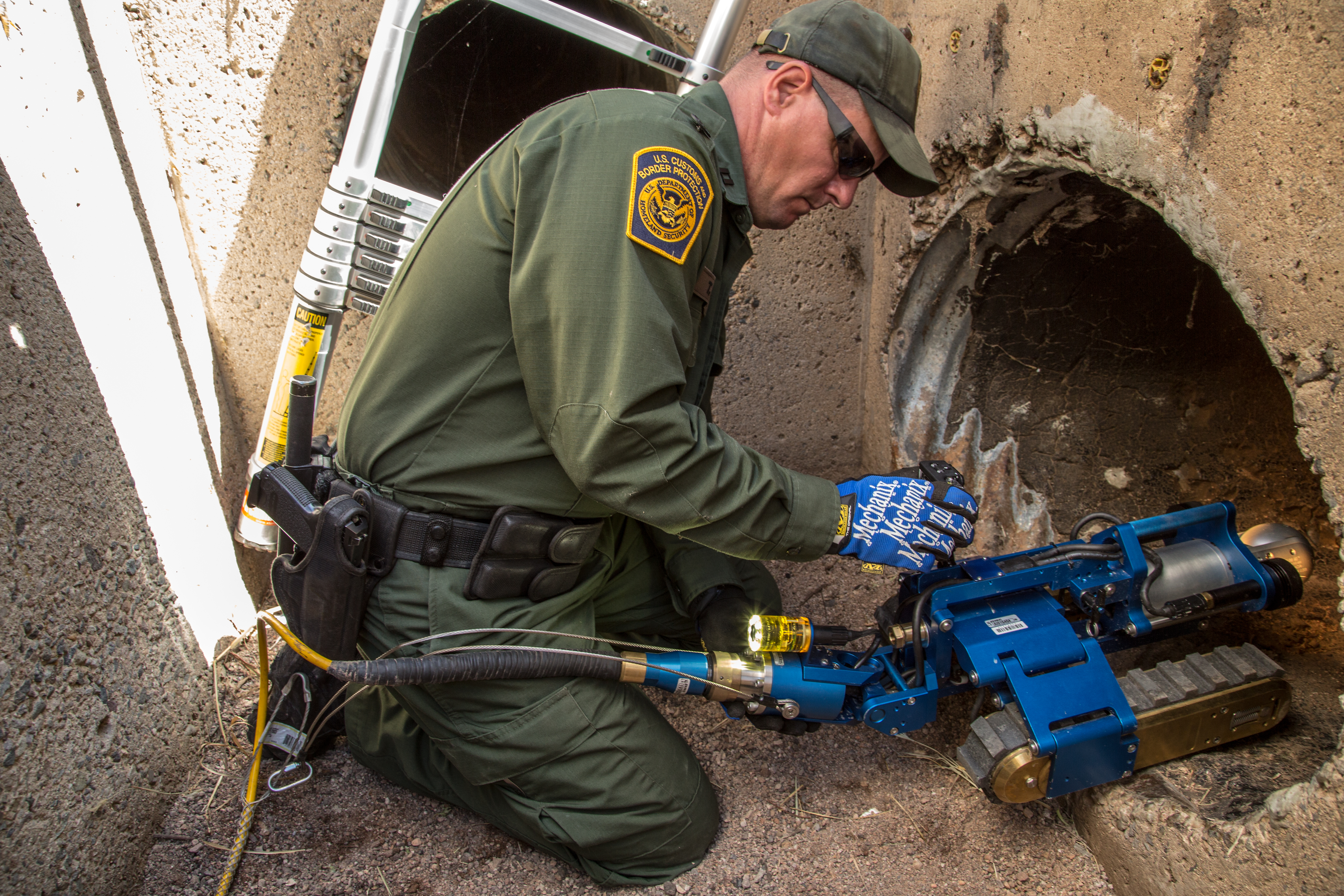 Supervisory Border Patrol Agent Thomas Pittman places the robot into the drainage pipe.
