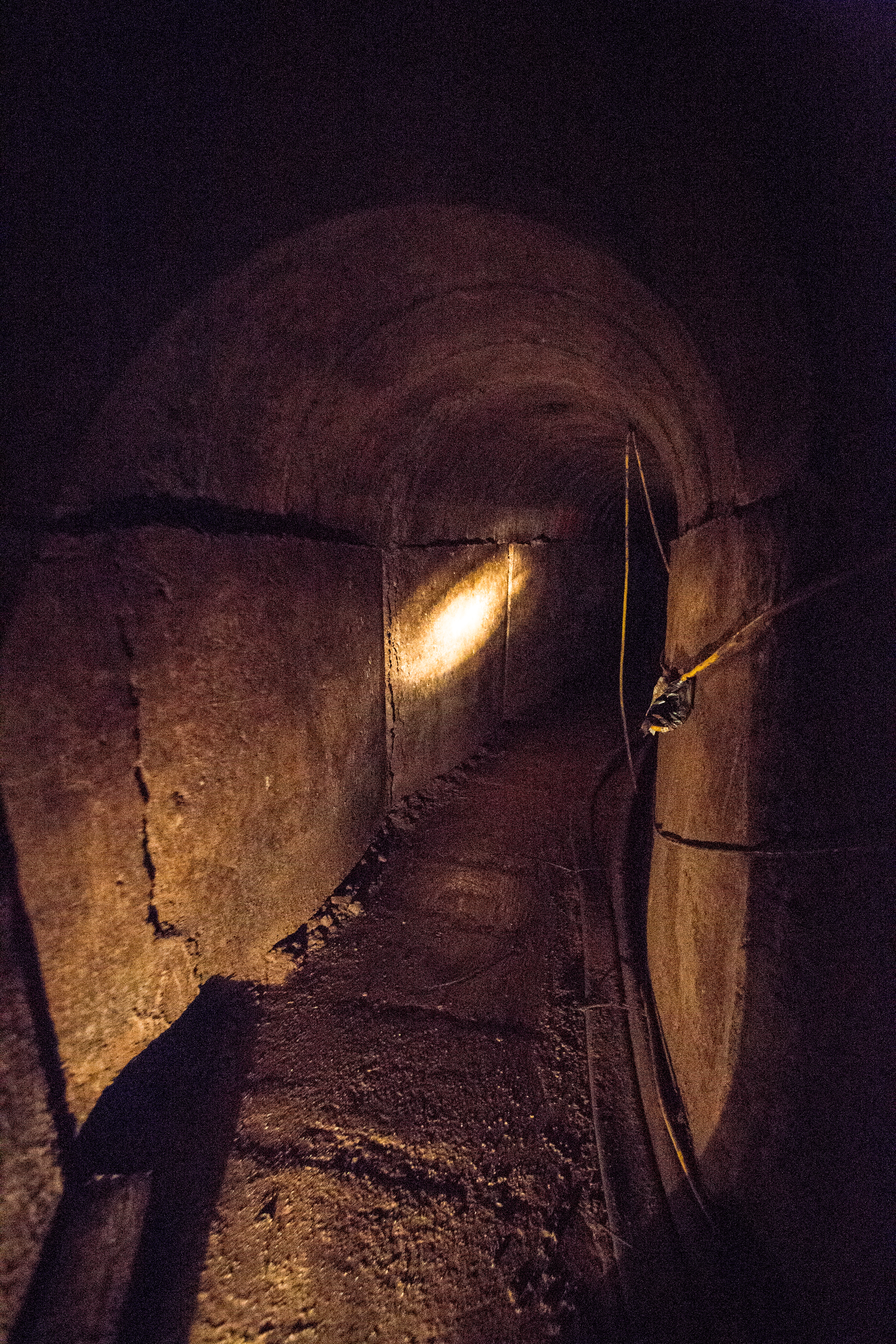 A Border Patrol agent shines his flashlight through the darkness in the Douglas Tunnel.