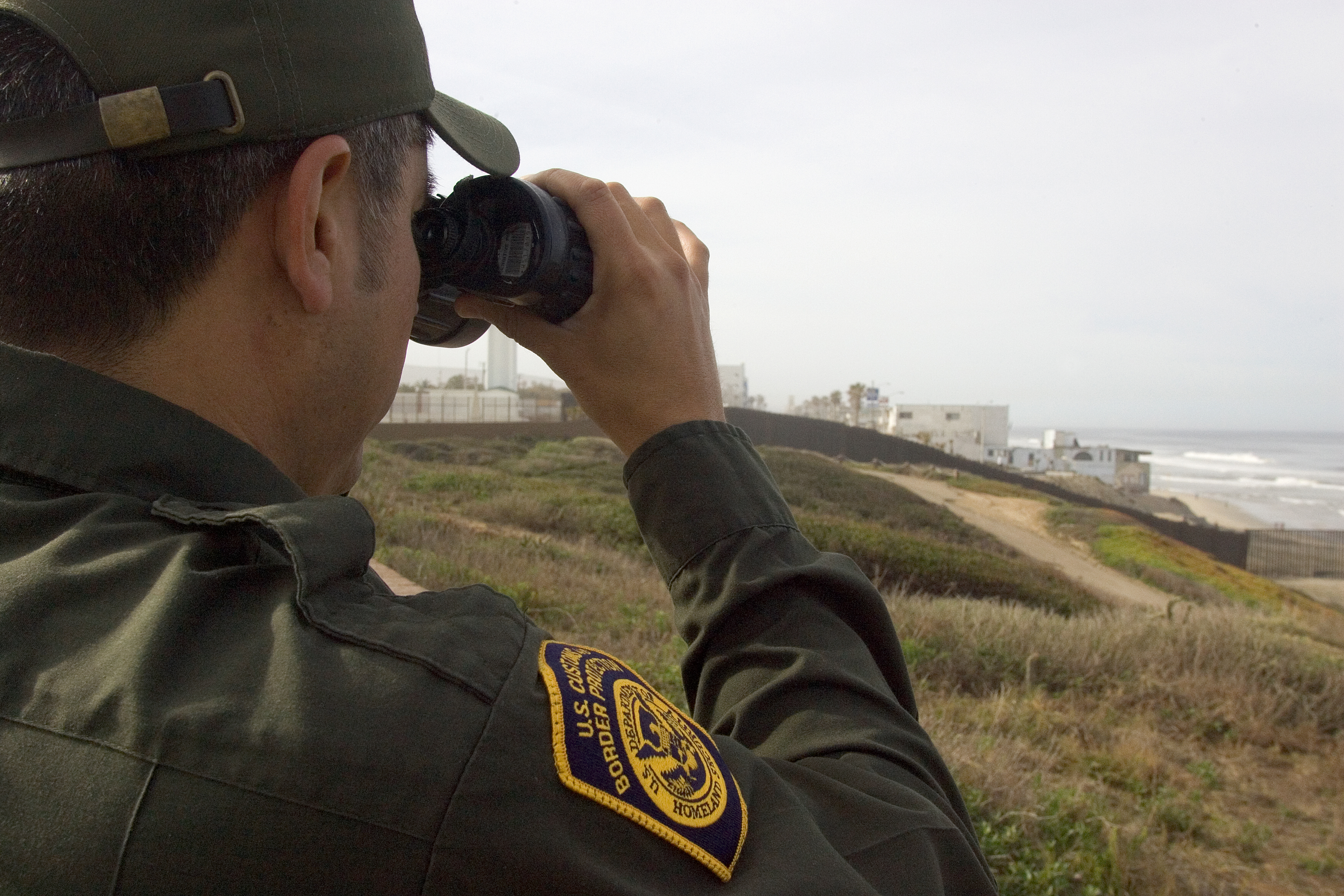 U.S. Border Patrol agent watches people as they gather next to the U.S./Mexico border in Imperial Valley, CA.