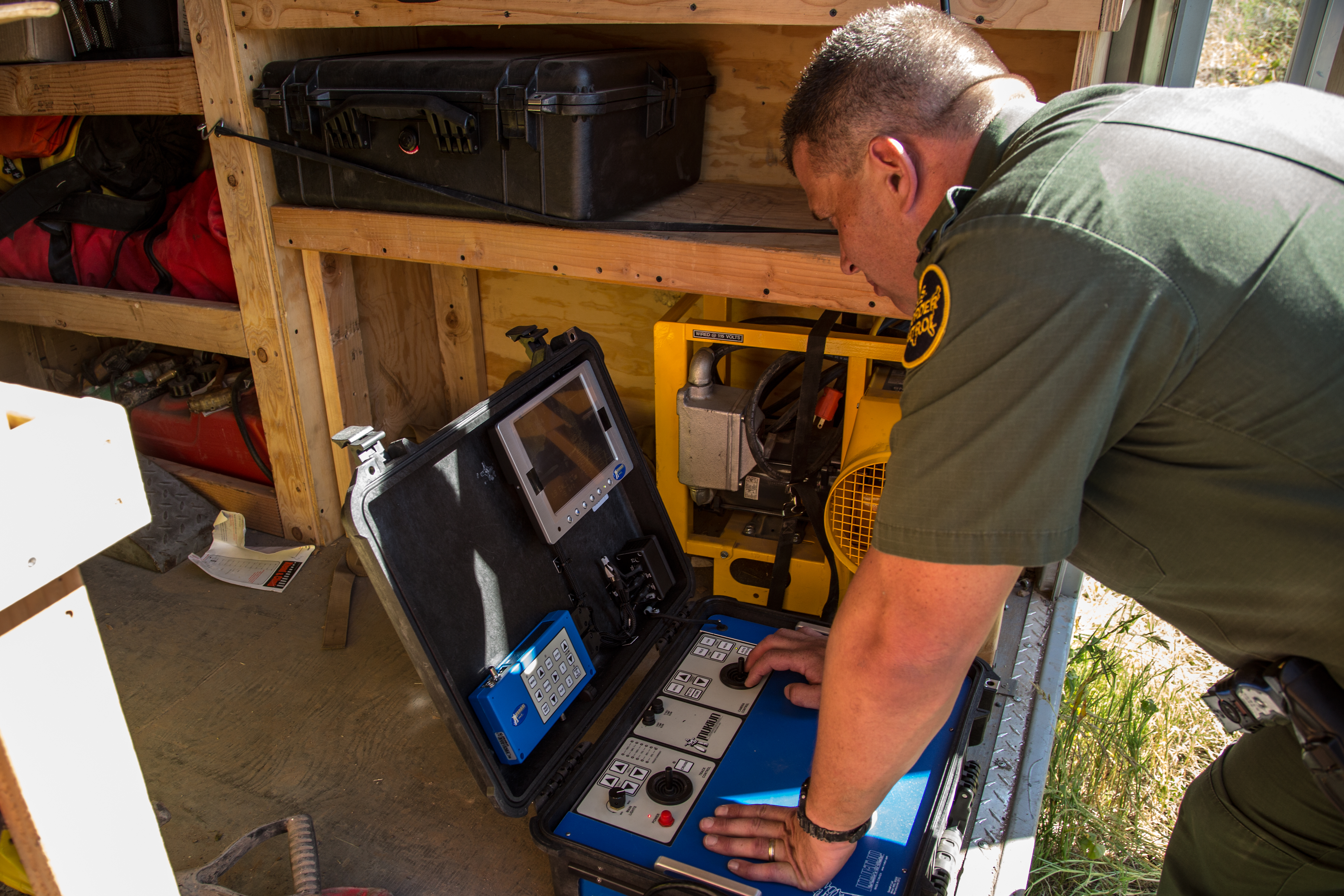 A Border Patrol agent prepares the robot's control console prior to deployment.