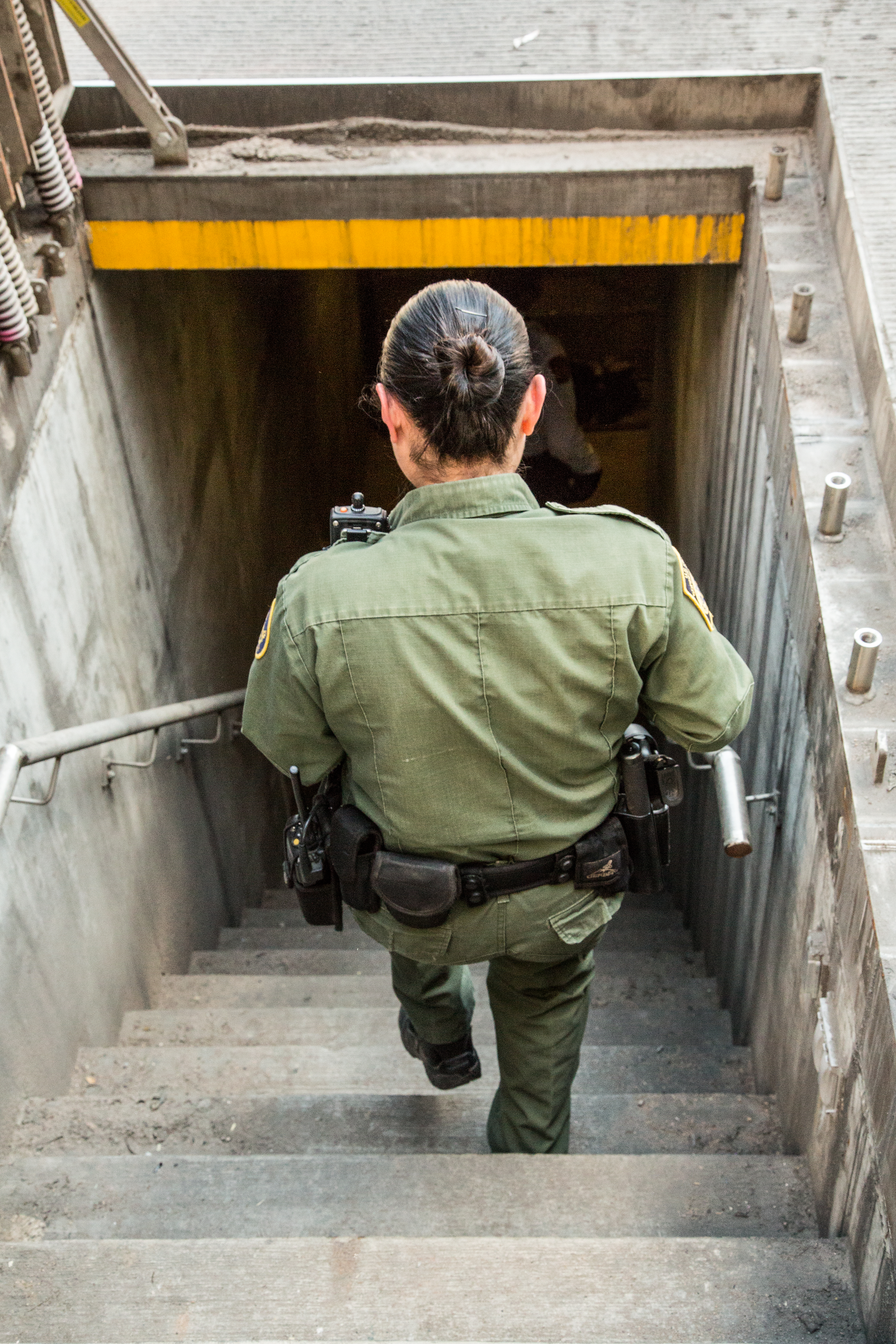 Border Patrol agent goes down stairs into drainage tunnel