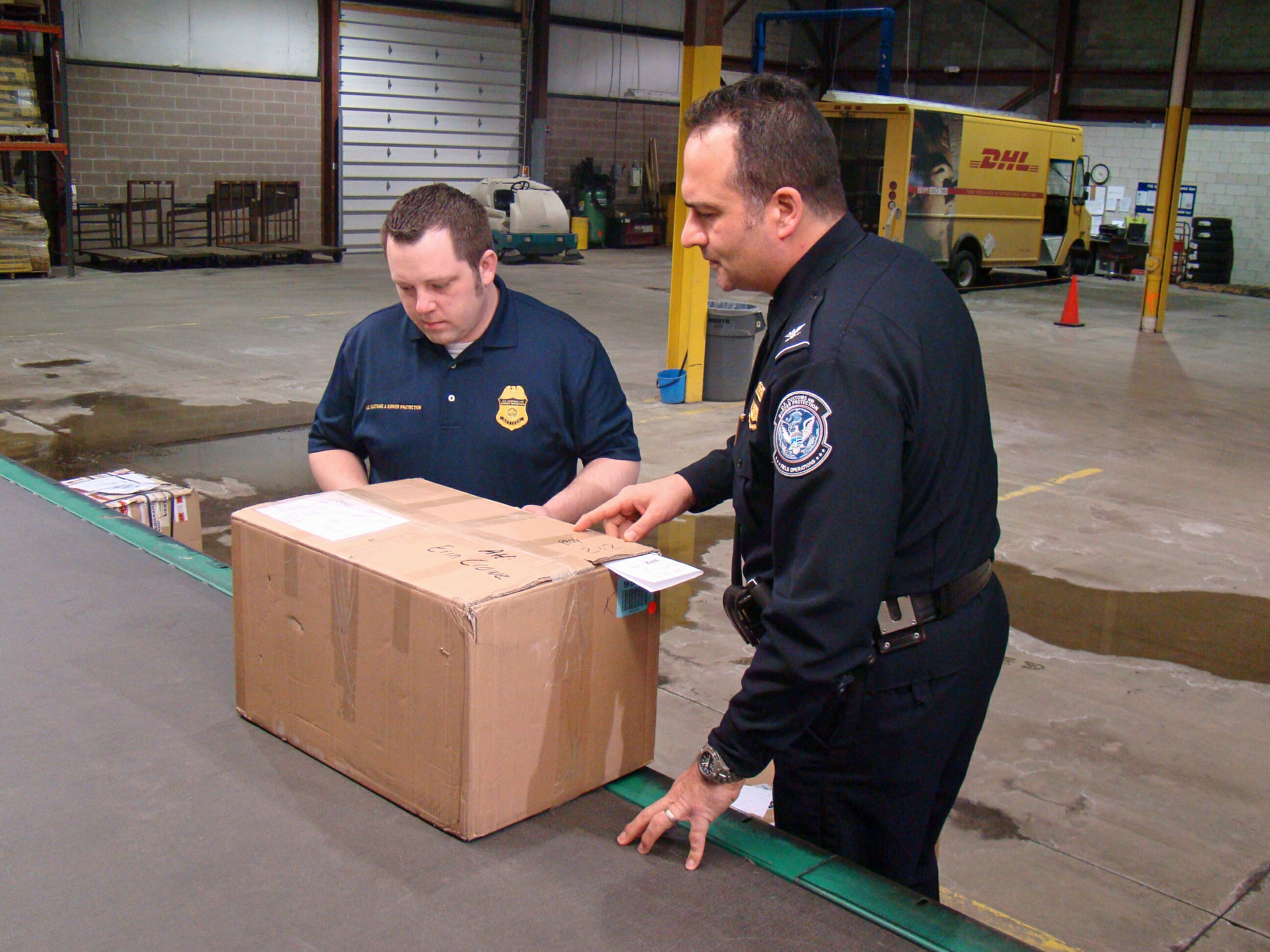 CBP Assistant Area Port Director of Cleveland Eugene Matho, right, and CBP Import Specialist John Parkinson prepare to inspect a shipment of suspected counterfeit DVDs at the DHL Express Courier Distribution Center in Cleveland. Photo by Gary Chaffee
