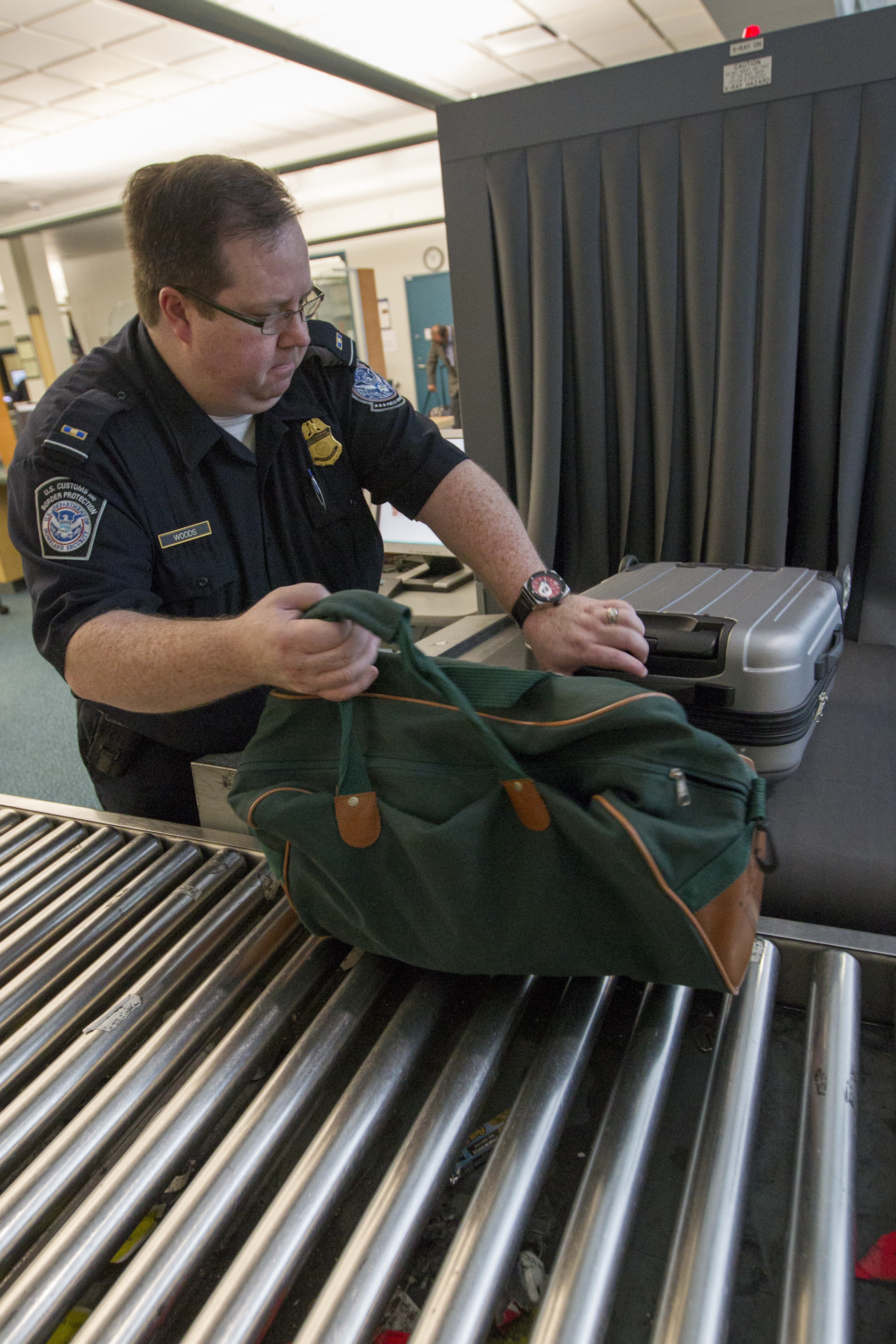 A CBP Vancouver preclearance officer handles bags identified for secondary examination.