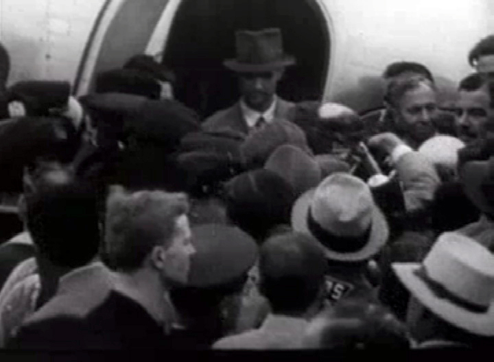 Howard Hughes in the doorway of his plane, surrounded by press and well-wishers, shortly after setting the round-the-world record.