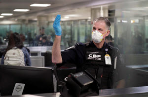 An officer with U.S. Customs and Border Protection gestures for arriving international travelers to proceed forward through the line at Dulles International Airport near Washington, D.C