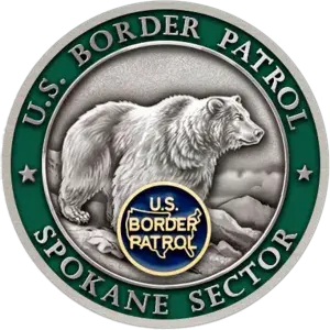 spokane challenge coin background is green and there is a grey bear on the front.
