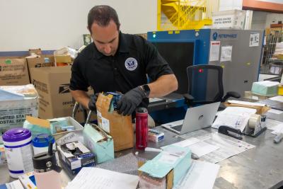 Paul Taylor, an Office of Trade specialist, inspects packages at the JFK Mail Facility in New York during Operation Bitter Pill
