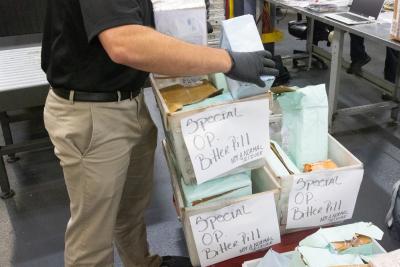 Office of Trade specialist goes through boxes during Operation Bitter Pill at the JFK Mail Facility in New York