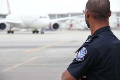 A CBP officer at Detroit Metropolitan Airport watches as an aircraft arrives at the terminal