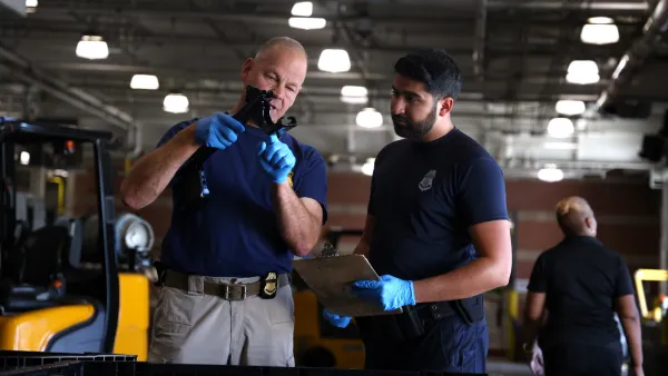 CBP Import Specialist and CBP Officer looking at component