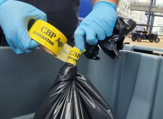 A CBP officer seals a bag with hazardous items.