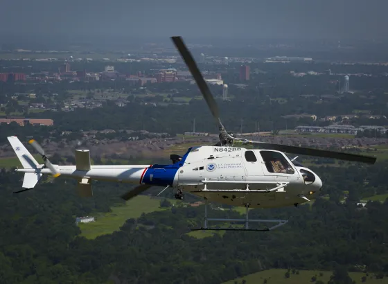 Photo of a CBP helicopter making a steep turn in the skies above Oklahoma City.