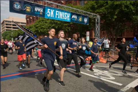 CBP officers and agents carrying flag across the finish line at National Police Week 5k