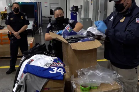 OFO officers examine counterfeit NFL items, such as jerseys, hats, and rings.