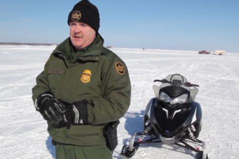 Border Patrol agent standing next to his snowmobile