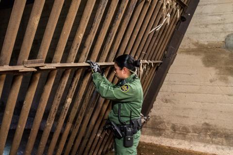 A Border Patrol agents looks through the steel security grates in a Nogales drainage tunnel.