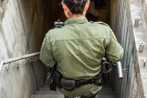 Border Patrol agent goes down stairs into drainage tunnel