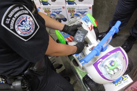 A CBP officer inspects a battery included in a child's toy vehicle.