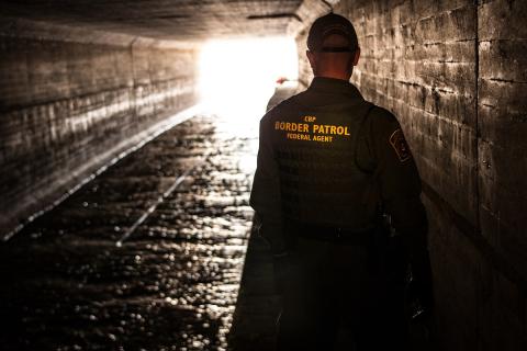 A Border Patrol agent observes the interior of a water drainage tunnel at the Arizona-Mexico border.