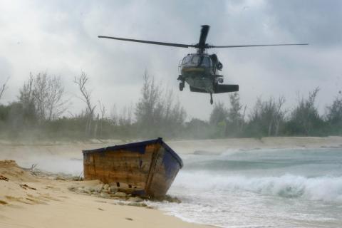 A CBP UH-60 Black Hawk helicopter flies over an island in Puerto Rico searching for people.