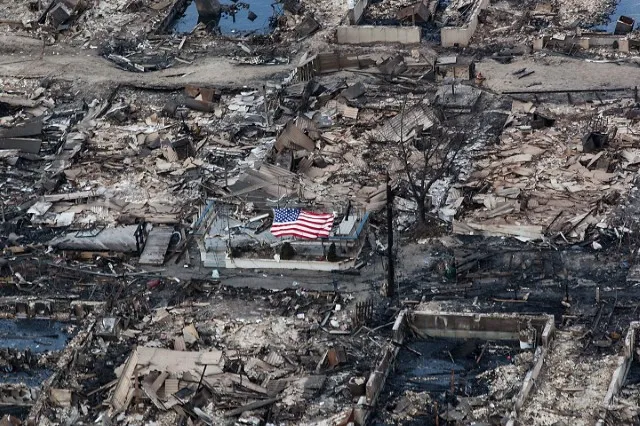 Photo of a flag amongst burnt homes