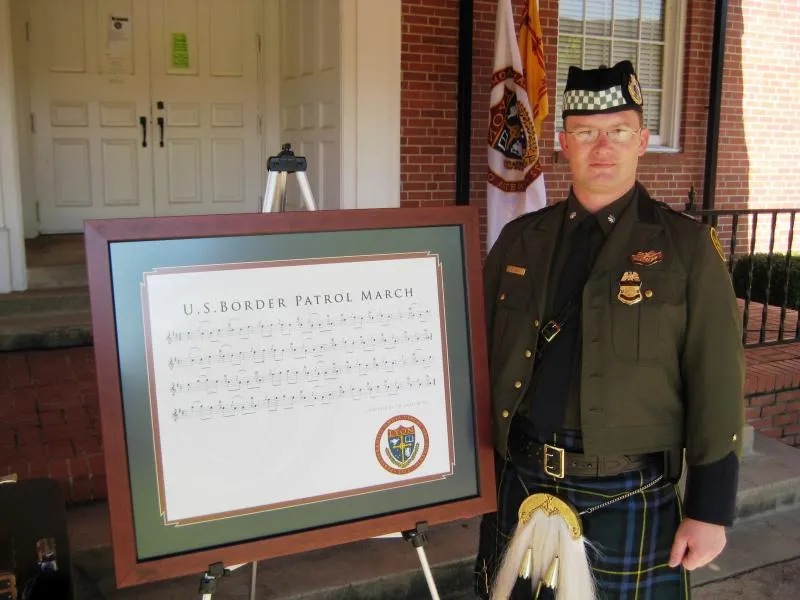 Assistant Chief Clifford Gill, then Commander of the USBP P&D, accepts a framed copy of the Border Patrol March, a gift of Gordon, James and Colin Bell of the Balmoral School of Piping and Drumming. It is currently on display at CBP Headquarters in the Office of Border Patrol. Photo April 2008.