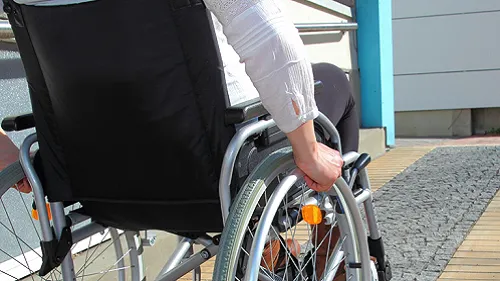 Woman in a wheelchair going up a ramp.