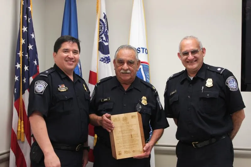 Supervisory CBP Agriculture Specialist Amando D. Garcia (center) holds a congratulatory wooden plaque as he poses with Assistant Port Director Alberto Flores (left) and Chief CBP Agriculture Specialist David Gonzalez (right) during a retirement luncheon held this week at World Trade Bridge.