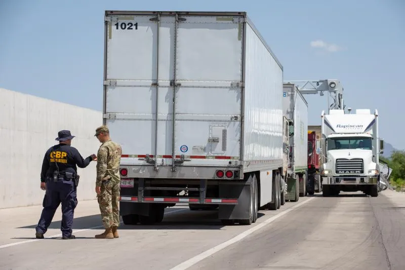 A CBP officer and National Guardsman queue semi-tractor trailers for non-intrusive inspections (NII) at the Port of Nogales in Nogales, Arizona
