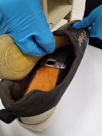 CBP Officer conducts secondary inspection of imposter's shoe and finds read ID card inside