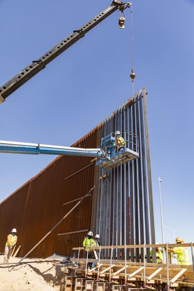 Construction workers install a 30-foot bollard wall panel.