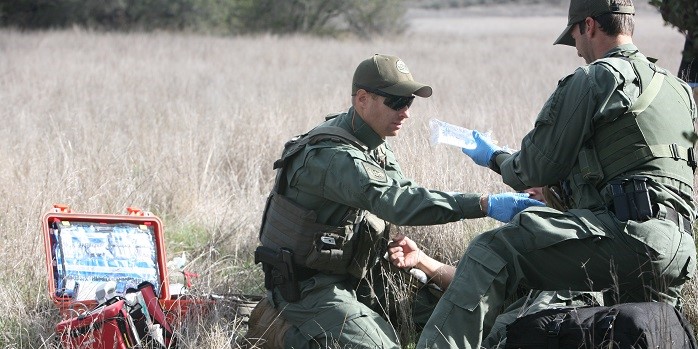 Border Patrol agents from the Mobile Response Team and Border Patrol Search Trauma and Rescue Team adminster fluids to a dehydrated woman in the brush south of Laredo