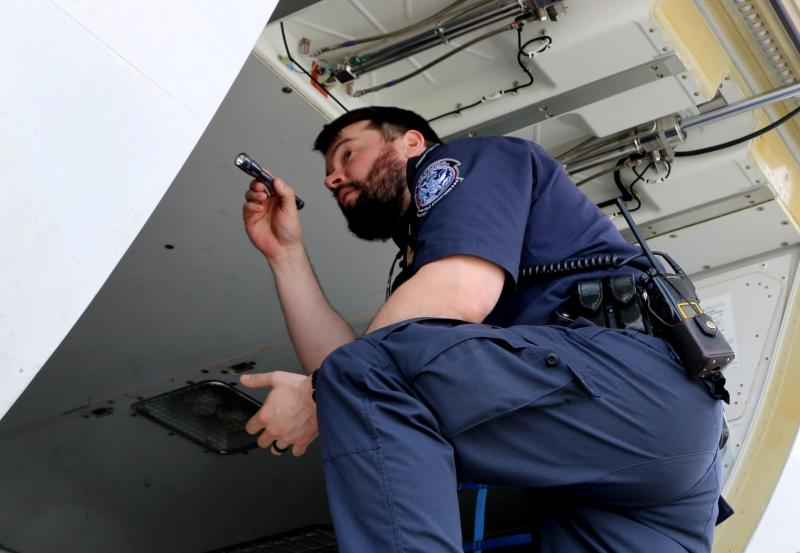 CBP officer inspects the cargo hold of an international aircraft for narcotics or other illicit products at Washington Dulles International Airport.