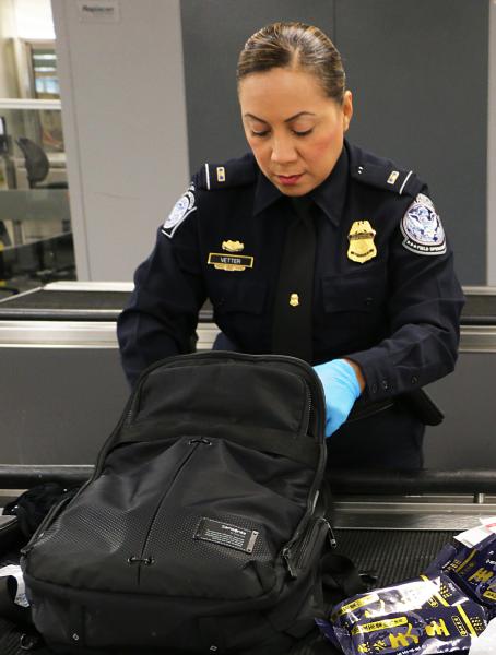 CBP officer inspecting a traveler's backpack.