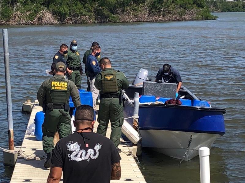 Border Patrol agents and PRPD Officers inspect the yola vessel after it was found hidden within mangroves. . 